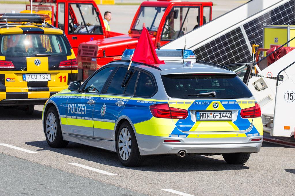 G20 Germany: Streifenwagen der Polizei mit roter Fahne |